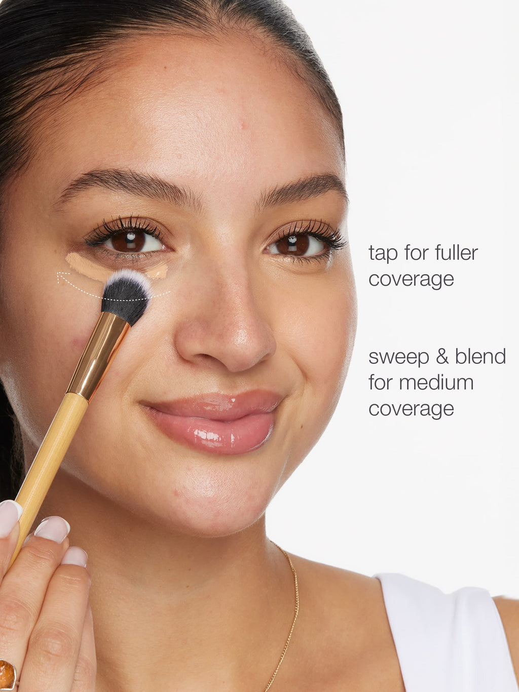 Woman applying makeup with a brush on her face, demonstrating coverage techniques.
