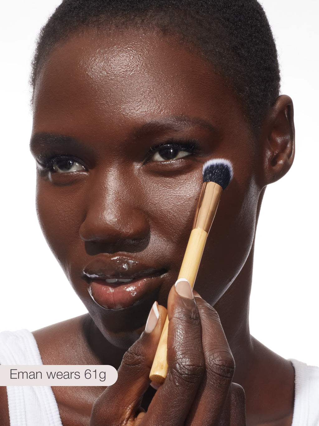 Woman applying makeup with a tarte concealer paw brush on a white background