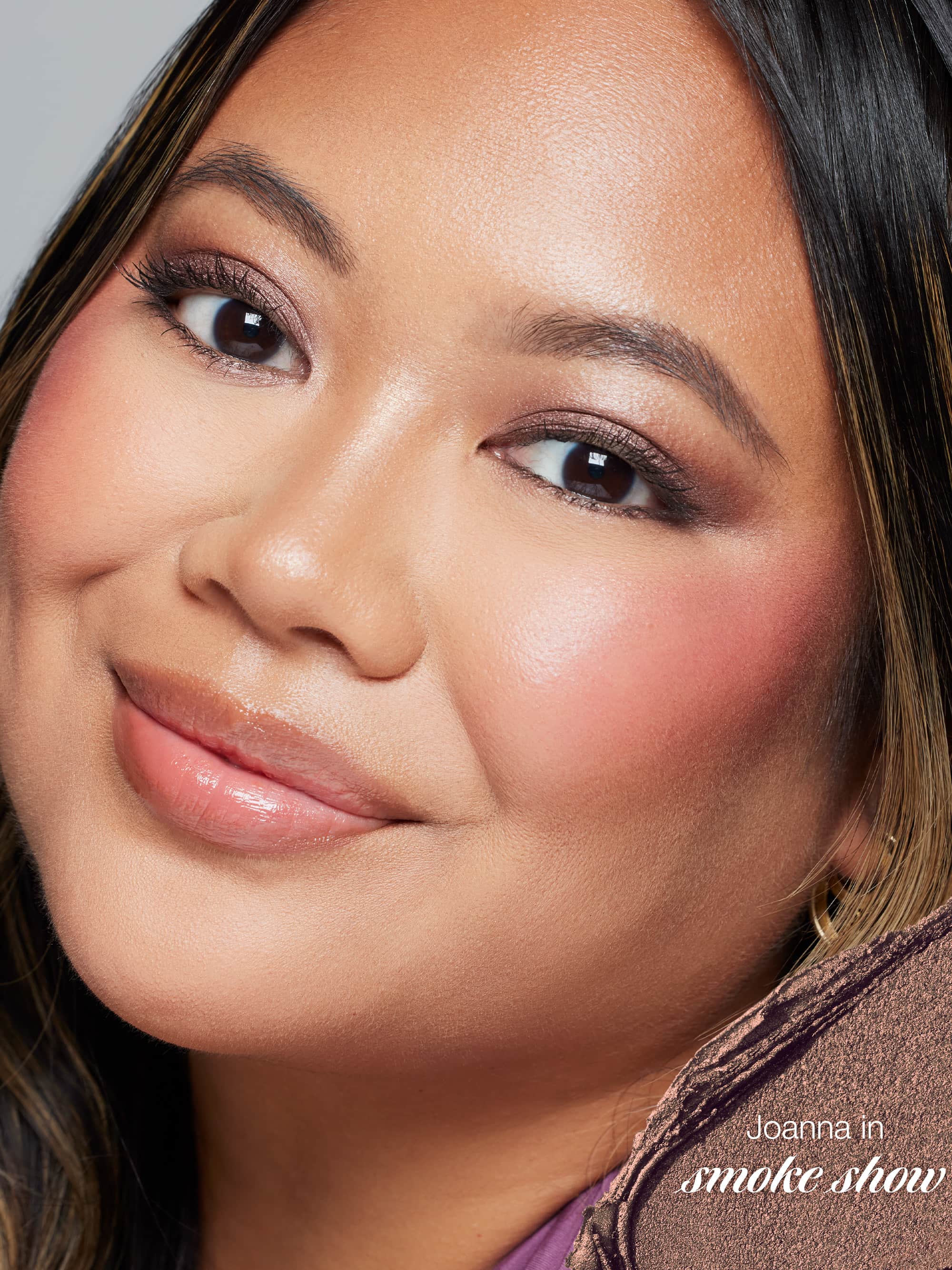 Close-up of a woman with makeup, featuring the brand 'Joanna' in 'smoke show' text.