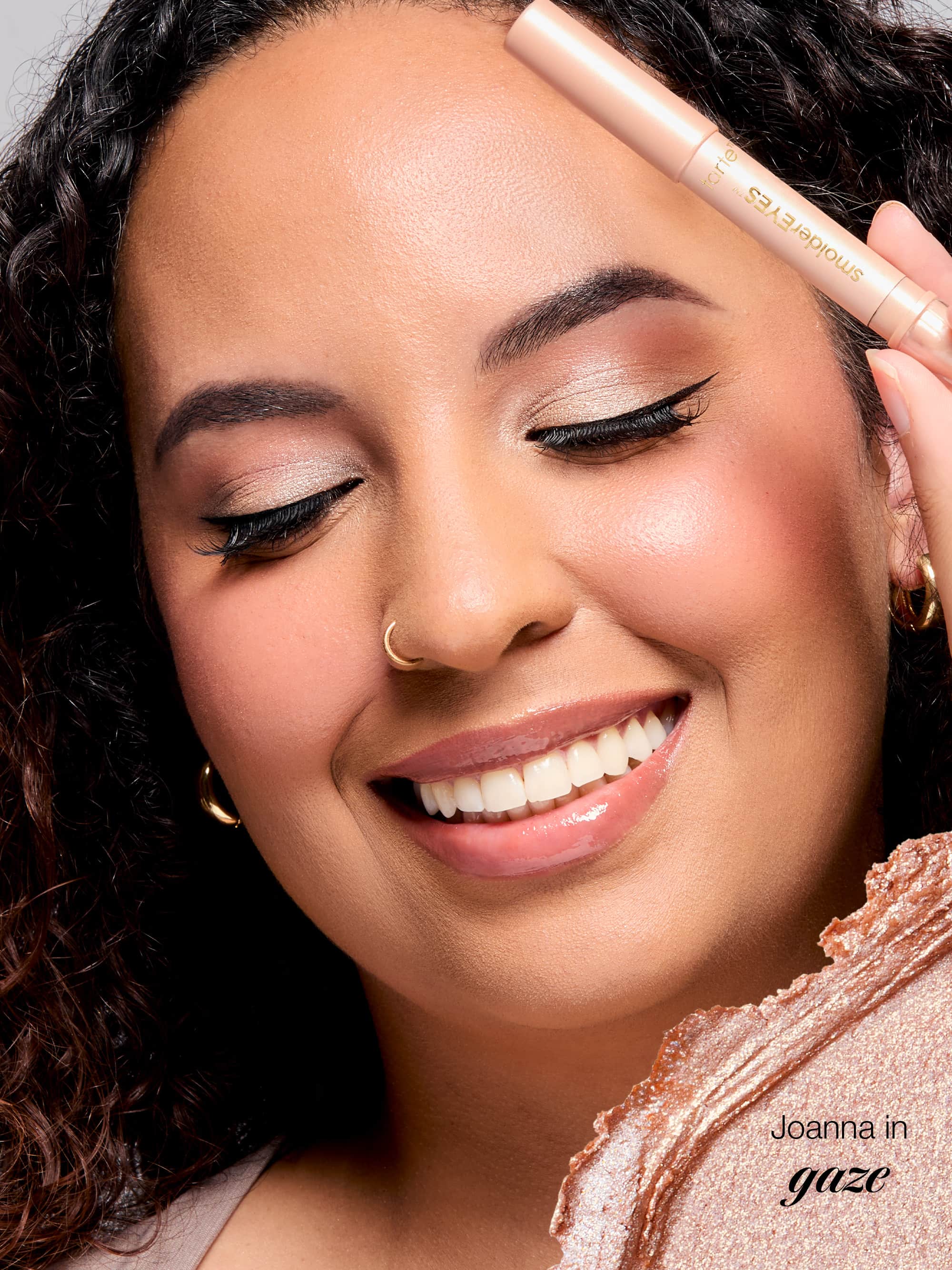 Woman applying makeup with a brush, wearing a gold hoop earring.